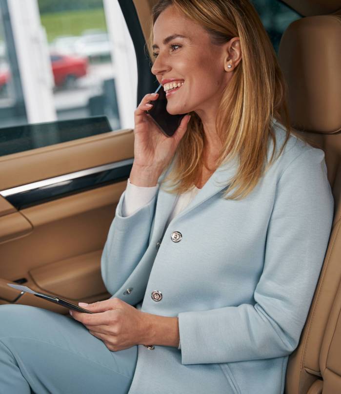 Smiling joyous elegant lady with boarding ticket talking on smartphone in car